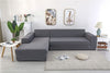 Funda de sofá ajustable en color gris claro en una sala de estar moderna, complementada con decoraciones minimalistas y plantas verdes. Ideal para proteger y renovar el aspecto del mobiliario, disponible en blueemoonco.com.