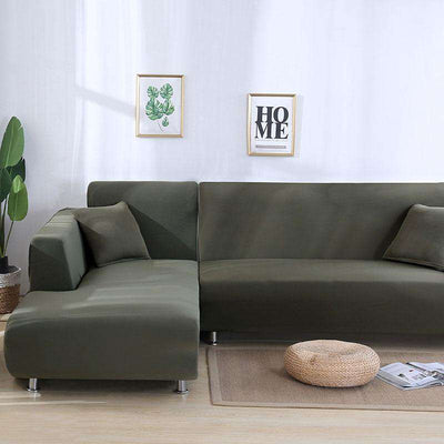 Sofá esquinero cubierto con funda verde oliva en un salón minimalista con decoración de plantas y cuadros