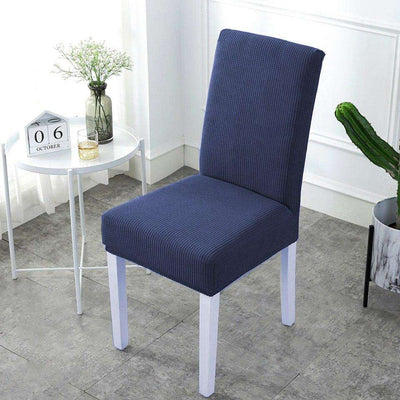 Funda para silla de color gris oscuro, de diseño elegante y ajuste universal, disponible en blueemoonco.com. Ideal para modernizar y proteger tus muebles de manera práctica y económica. Ambiente luminoso y contemporáneo con decoración minimalista.