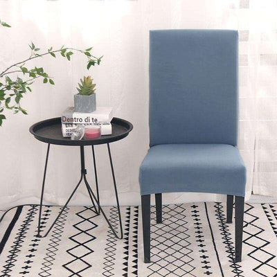 Fundas para sillas azules elegantes sobre silla moderna en decoración de interior con mesa auxiliar y planta, perfectas para renovar y proteger el mobiliario de tu hogar.