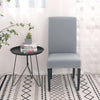 Funda de silla gris claro de blueemoonco.com en un entorno moderno con mesa auxiliar y decoración minimalista.
