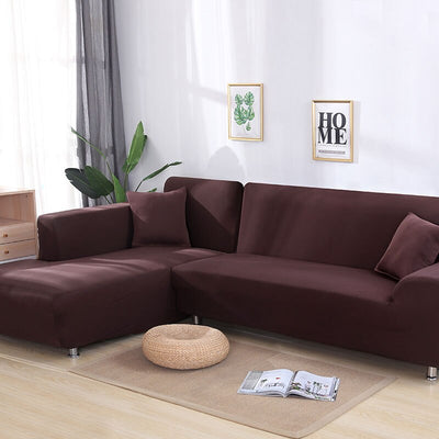 Funda de sofá elástica color marrón en sala de estar moderna con plantas decorativas y cuadros con mensajes de 'hogar', perfecta para la renovación de muebles.