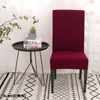 Funda para silla color rojo de blueemoonco.com, perfecta para decoración moderna y elegante. Presentada en un ambiente luminoso con detalles decorativos y alfombra de patrones geométricos.