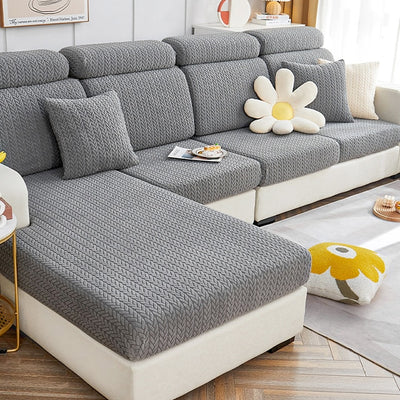 Fundas de sofá de diseño modular en gris con patrón de espiga, incluyendo cojines decorativos en forma de flor y amarillo, ideales para decoración de interiores moderna y práctica.