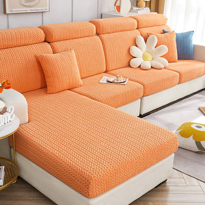 Fundas para sofá de color naranja con textura en forma de V, con cojines a juego, en una sala de estar luminosa y decorada con estilo. Compra disponible en blueemoonco.com, especialistas en fundas para sofás y sillas.