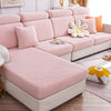 Fundas para sofá en tonos rosa pastel con diseño de textura geométrica, complementadas con cojines decorativos en naranja y diseño floral, perfectas para modernizar y proteger tus muebles. Disponibles en blueemoonco.com, tu tienda de fundas de sofá y sillas en la UE.