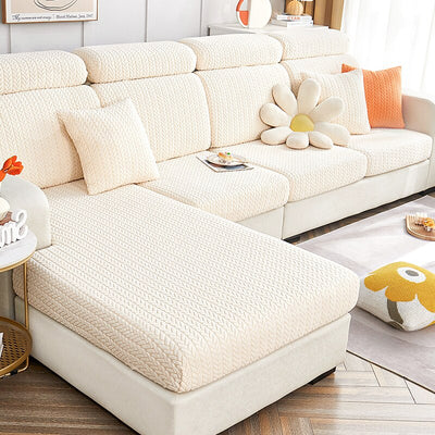 Funda de sofá beige texturizada en un salón moderno, con cojines a juego y una alfombra clara en el suelo. Decoración acogedora y contemporánea ideal para hogares elegantes. Disponible en blueemoonco.com.