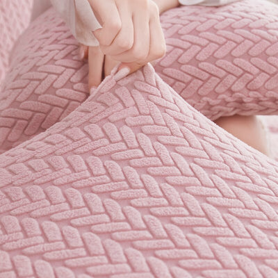Manos ajustando una funda de cojín texturizada en color rosa pastel, perfecta para sofás y sillas, disponible en blueemoonco.com