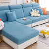 Funda de sofá de color azul texturizado en un sofá de esquina con cojines decorativos de diferentes colores y patrones en un salón bien iluminado, destacando la calidad y el diseño moderno de las fundas de BlueeMoonCo.com